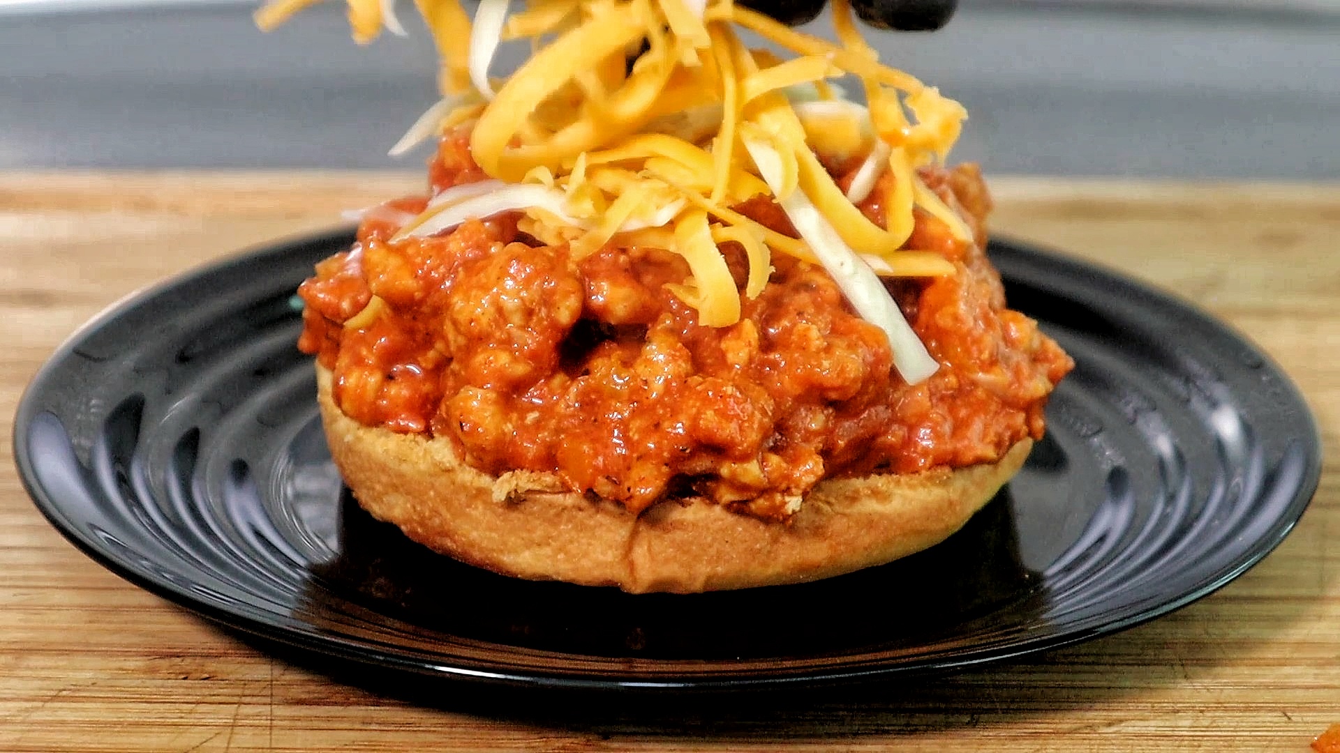 Cajun Chicken Sloppy Joe served on a toasted hamburger bun, filled with a savory mix of ground chicken in tomato-based Cajun sauce, topped with melted cheddar and mozzarella cheese. 