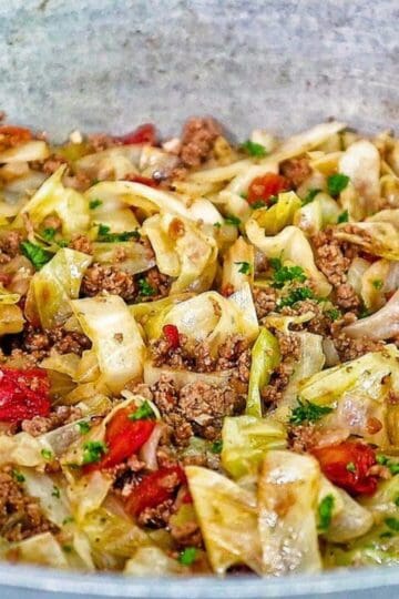 A skillet filled with sautéed cabbage, ground beef, diced tomatoes, and herbs, cooked to perfection in a large pot.