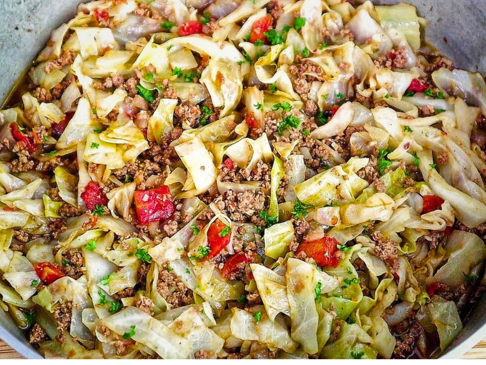 A skillet filled with sautéed cabbage, ground beef, diced tomatoes, and herbs, cooked to perfection in a large pot.