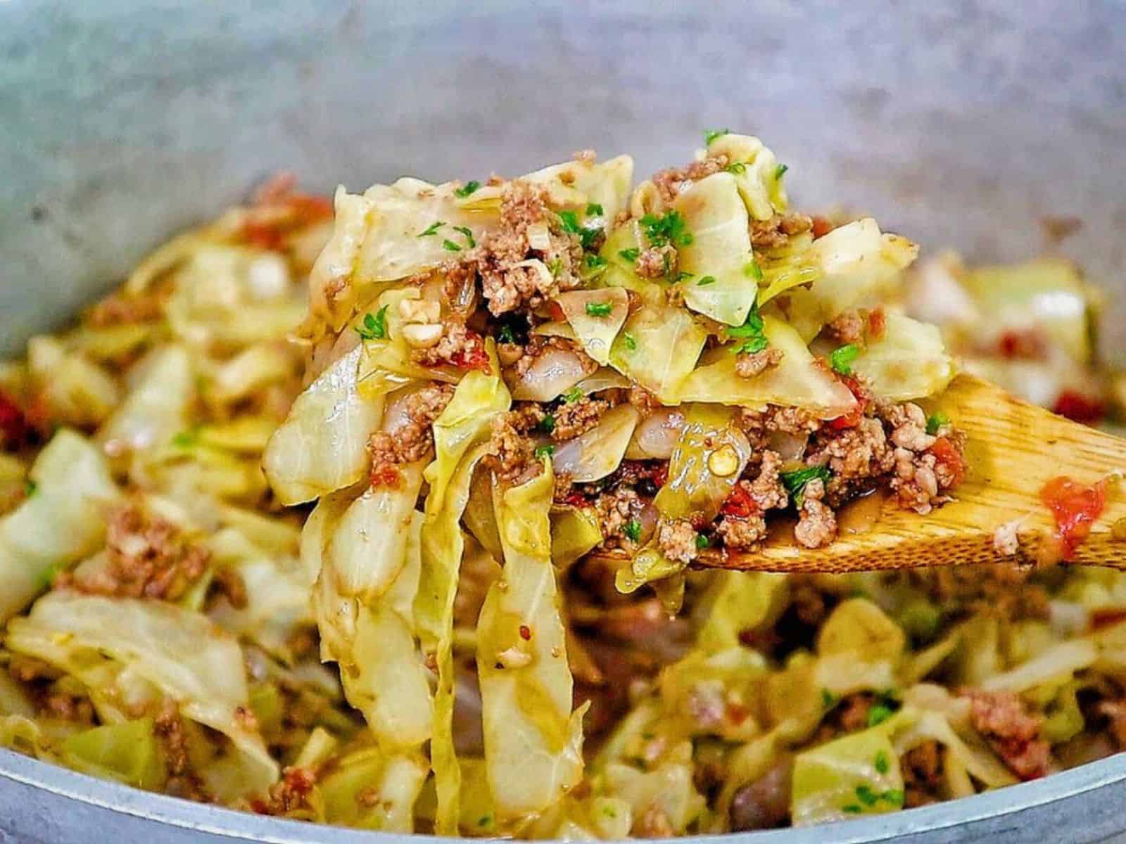 A skillet filled with sautéed cabbage, ground beef, diced tomatoes, and herbs, cooked to perfection in a large pot.