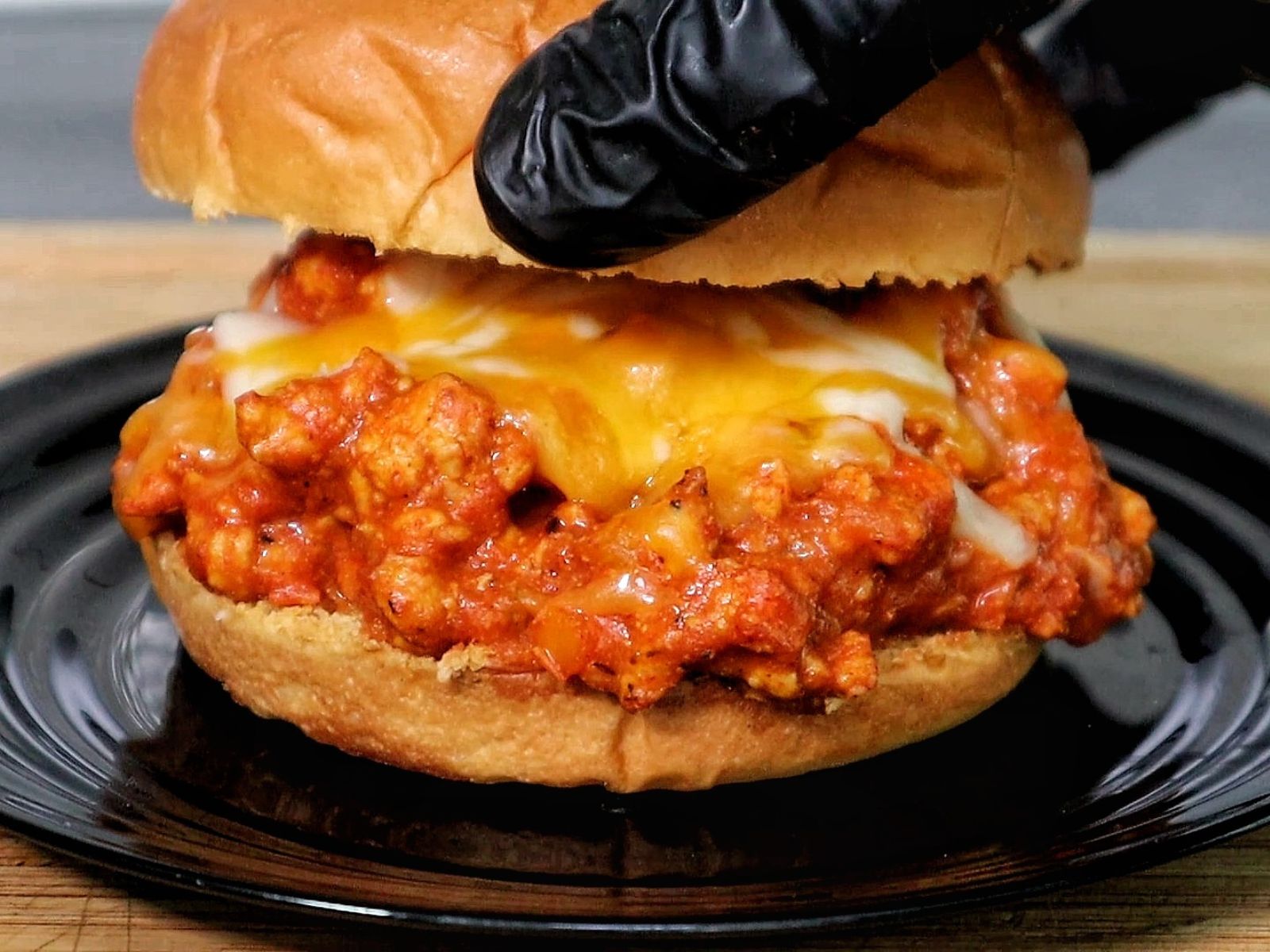 A Cajun Chicken Sloppy Joe served on a toasted hamburger bun, filled with a savory mix of ground chicken in tomato-based Cajun sauce, topped with melted cheddar and mozzarella cheese. 