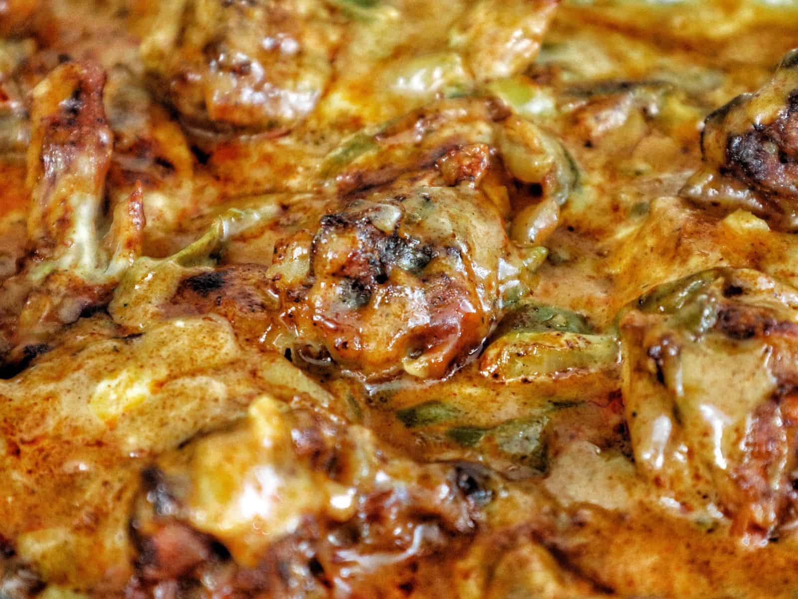 Close-up of juicy Cajun smothered chicken wings baked in a rich, creamy, golden-brown sauce with bits of peppers and onions.