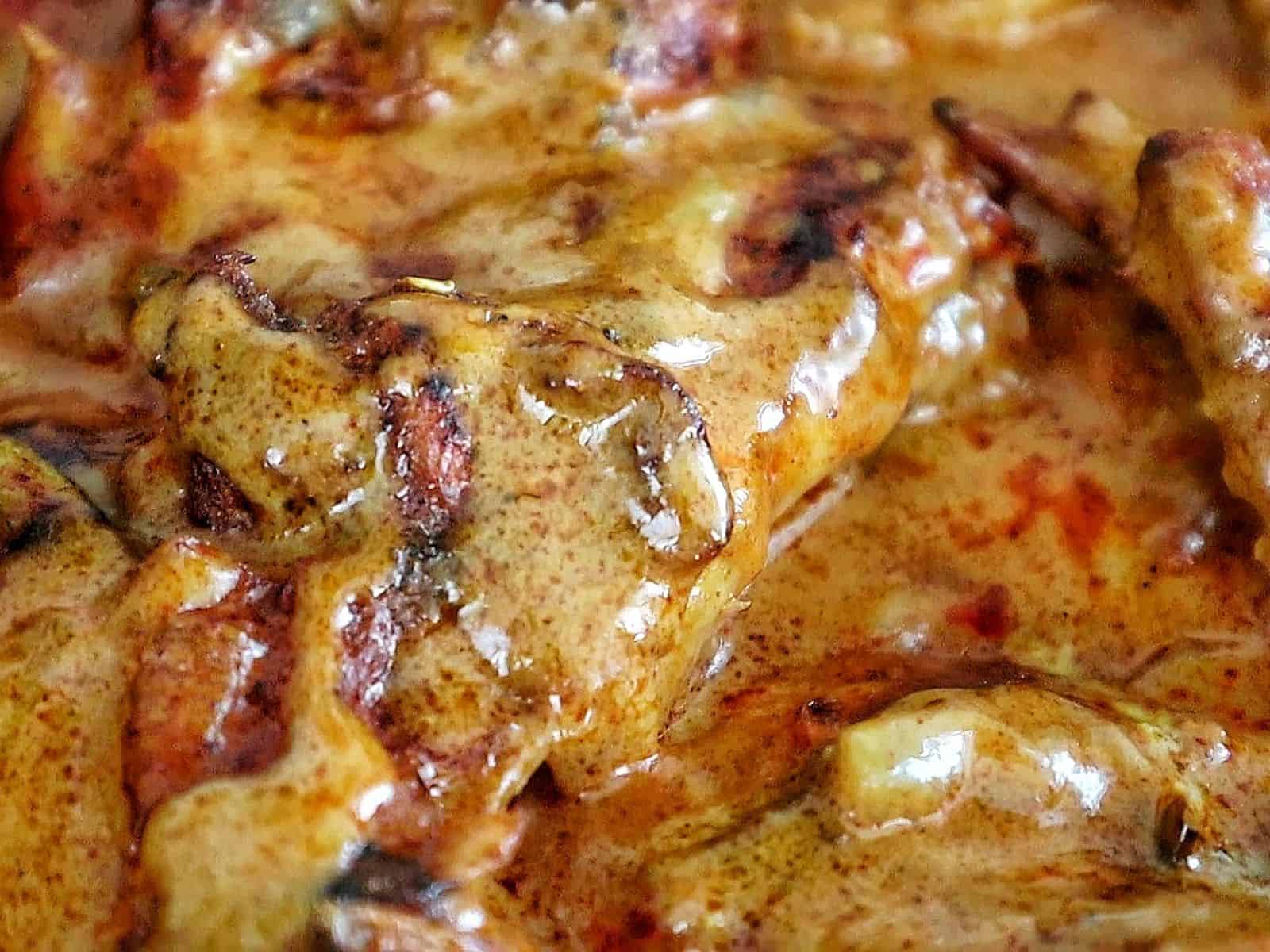 Close-up of juicy Cajun smothered chicken wings baked in a rich, creamy, golden-brown sauce with bits of peppers and onions.