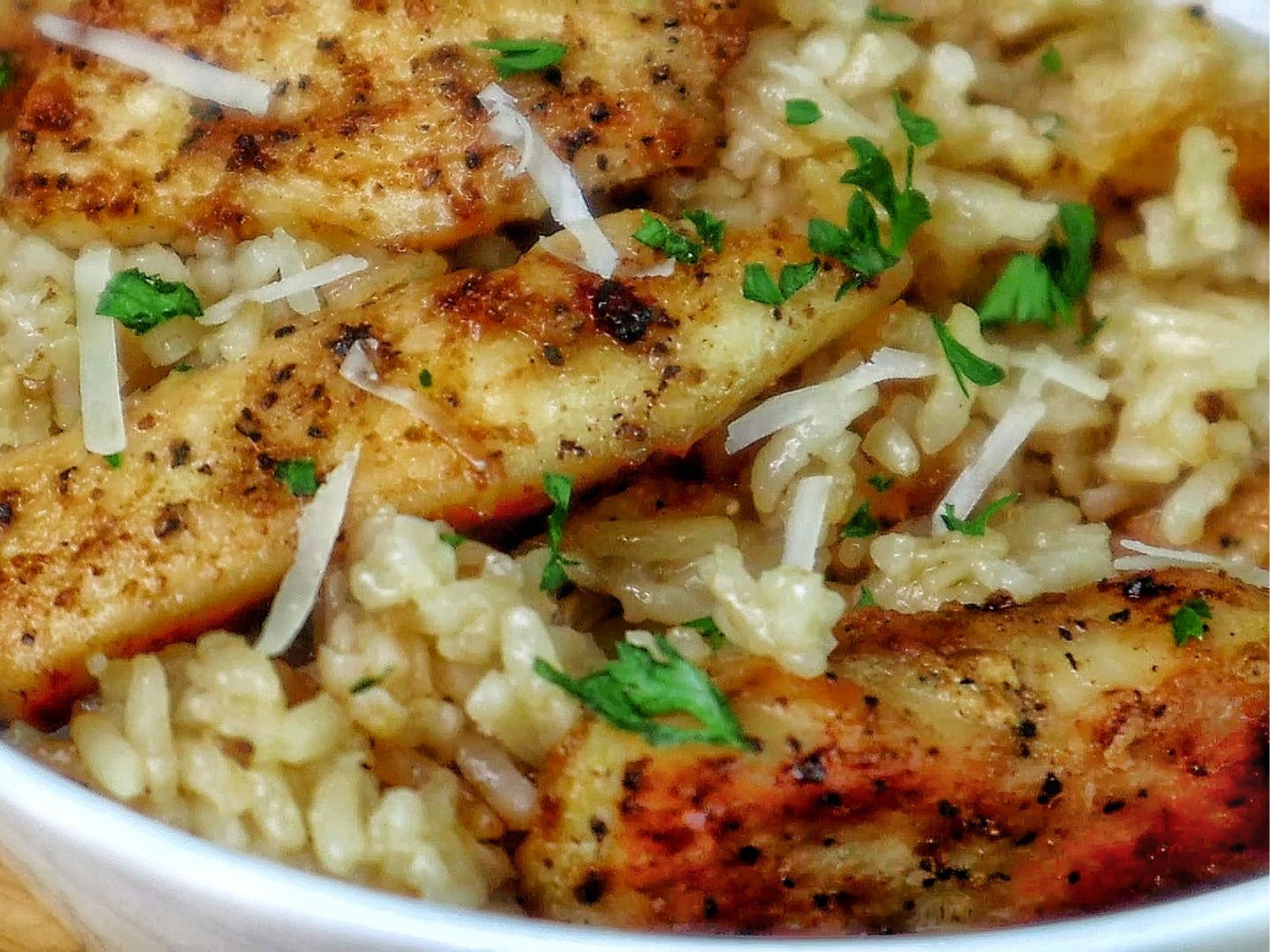 Golden brown seasoned chicken tenders on a bed of creamy garlic Parmesan rice, garnished with fresh parsley and parmesan cheese.