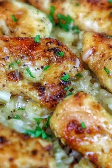 Golden brown seasoned chicken tenders on a bed of creamy garlic Parmesan rice, garnished with fresh parsley and parmesan cheese.