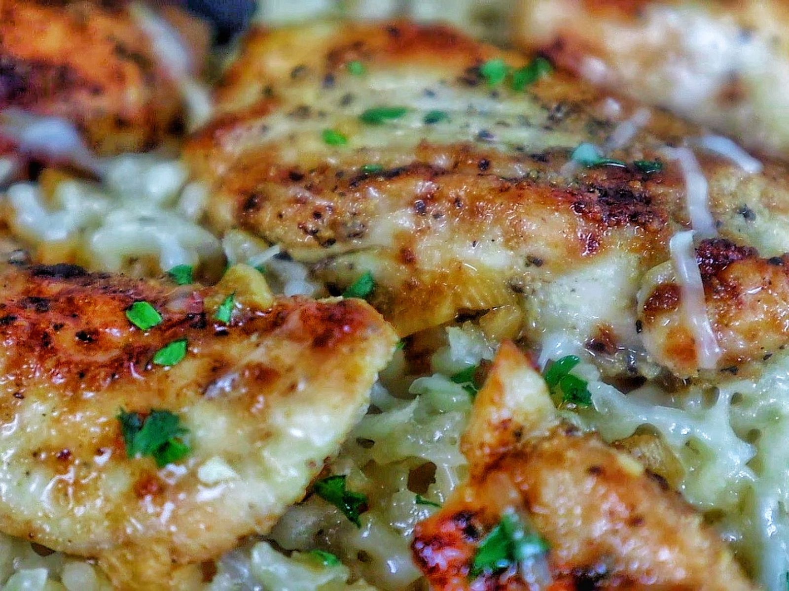 Golden brown seasoned chicken tenders on a bed of creamy garlic Parmesan rice, garnished with fresh parsley and parmesan cheese.