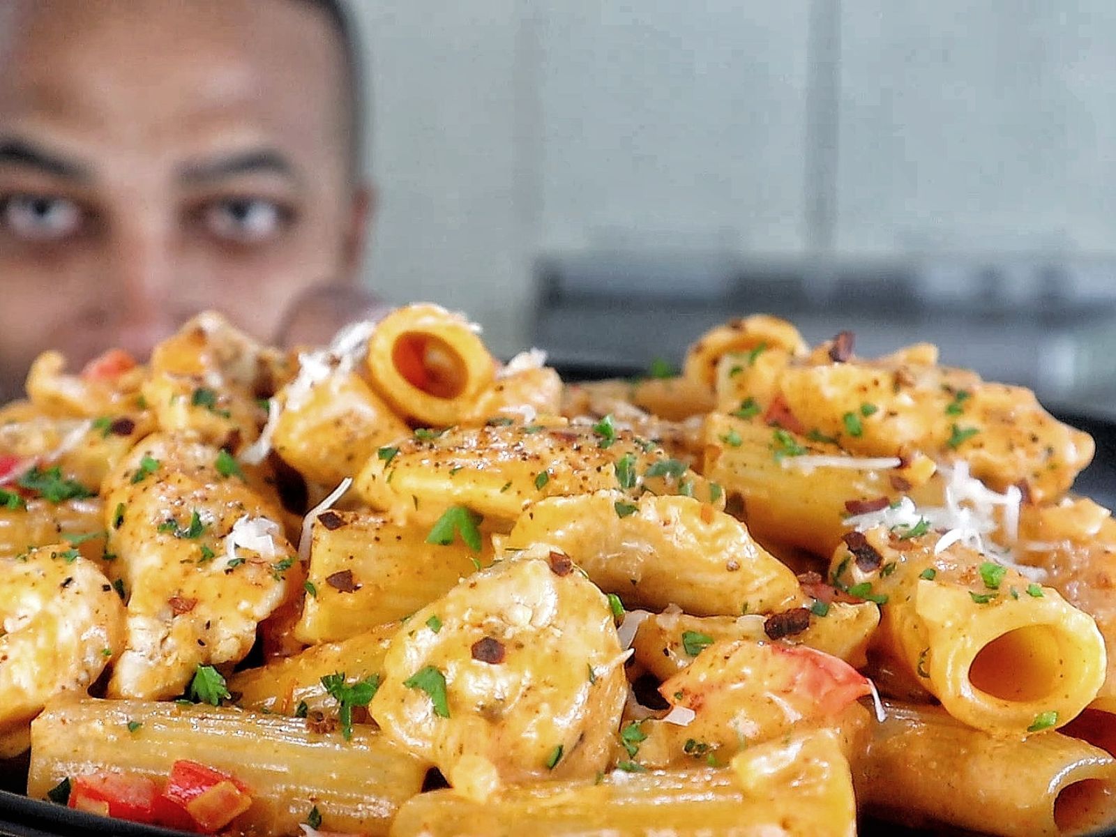 A plate of creamy Cajun chicken pasta made with rigatoni, tender chicken, red bell peppers, and a spicy Cajun cream sauce, garnished with chopped parsley and grated cheese.
