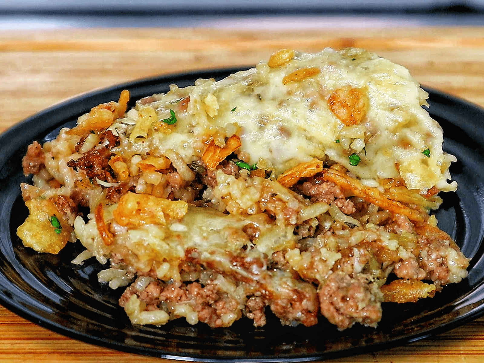 A close-up of a spoonful of French Onion Ground Beef and Rice Casserole, featuring tender ground beef, cooked rice, melted Swiss cheese, and crispy fried onions.