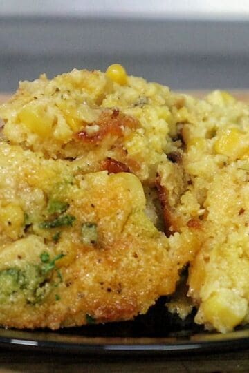 A close-up of a rich and golden honey glaze corn casserole being served from a baking dish. The texture looks soft, moist, and slightly crisp on top, with bits of corn visible throughout.