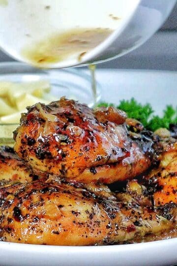 Golden brown, slow-cooked Italian garlic chicken thighs in savory juices, served with tender garlic cloves.