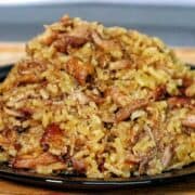 Close-up of a full serving of country-style ribs and rice, featuring tender, shredded rib meat mixed with seasoned, fluffy rice on a black plate.
