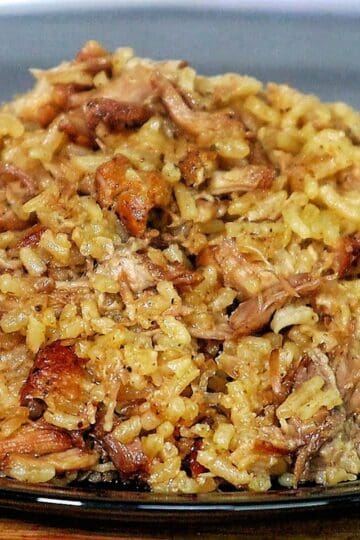 Close-up of a full serving of country-style ribs and rice, featuring tender, shredded rib meat mixed with seasoned, fluffy rice on a black plate.