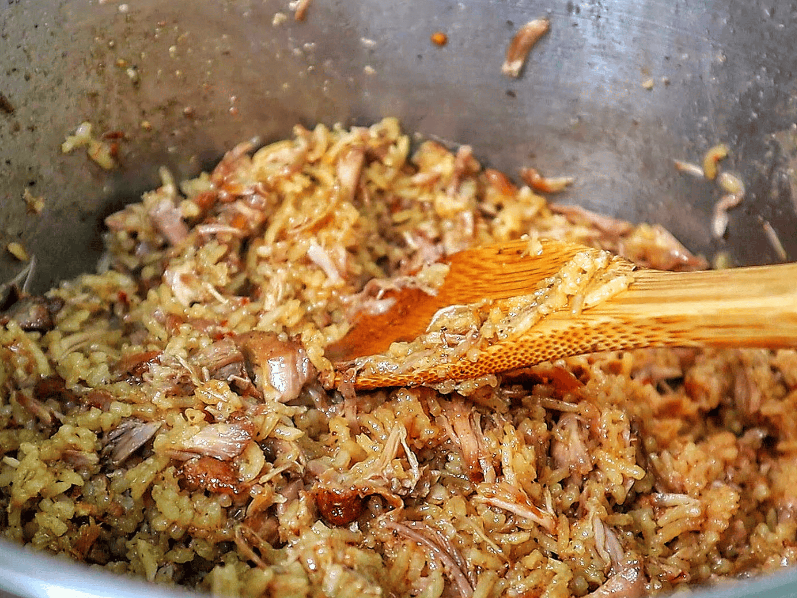 Close-up of a full serving of country-style ribs and rice, featuring tender, shredded rib meat mixed with seasoned, fluffy rice on a black plate.