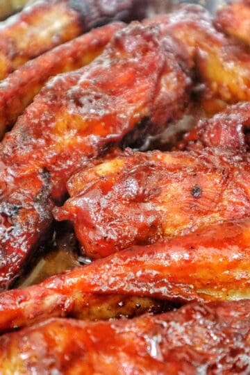 A close-up of juicy smoked BBQ ribs fresh off a pellet grill. The ribs are coated in a barbecue sauce with a deep caramelized glaze and visible char marks, highlighting their smoky, tender texture.
