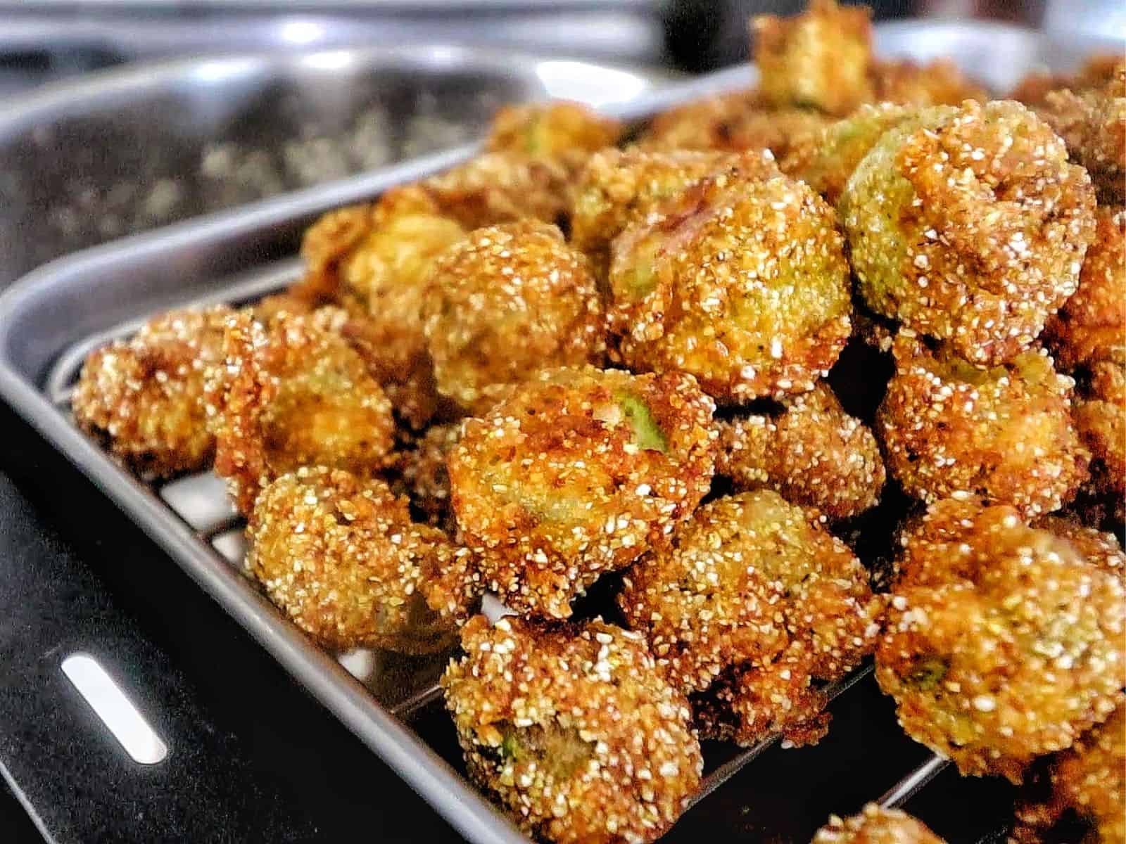 Golden brown Southern fried okra on a wire rack, crispy and seasoned with a cornmeal crust.