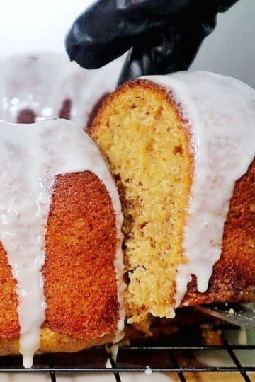 A moist sweet potato bundt cake topped with a smooth vanilla glaze, dripping down the sides.