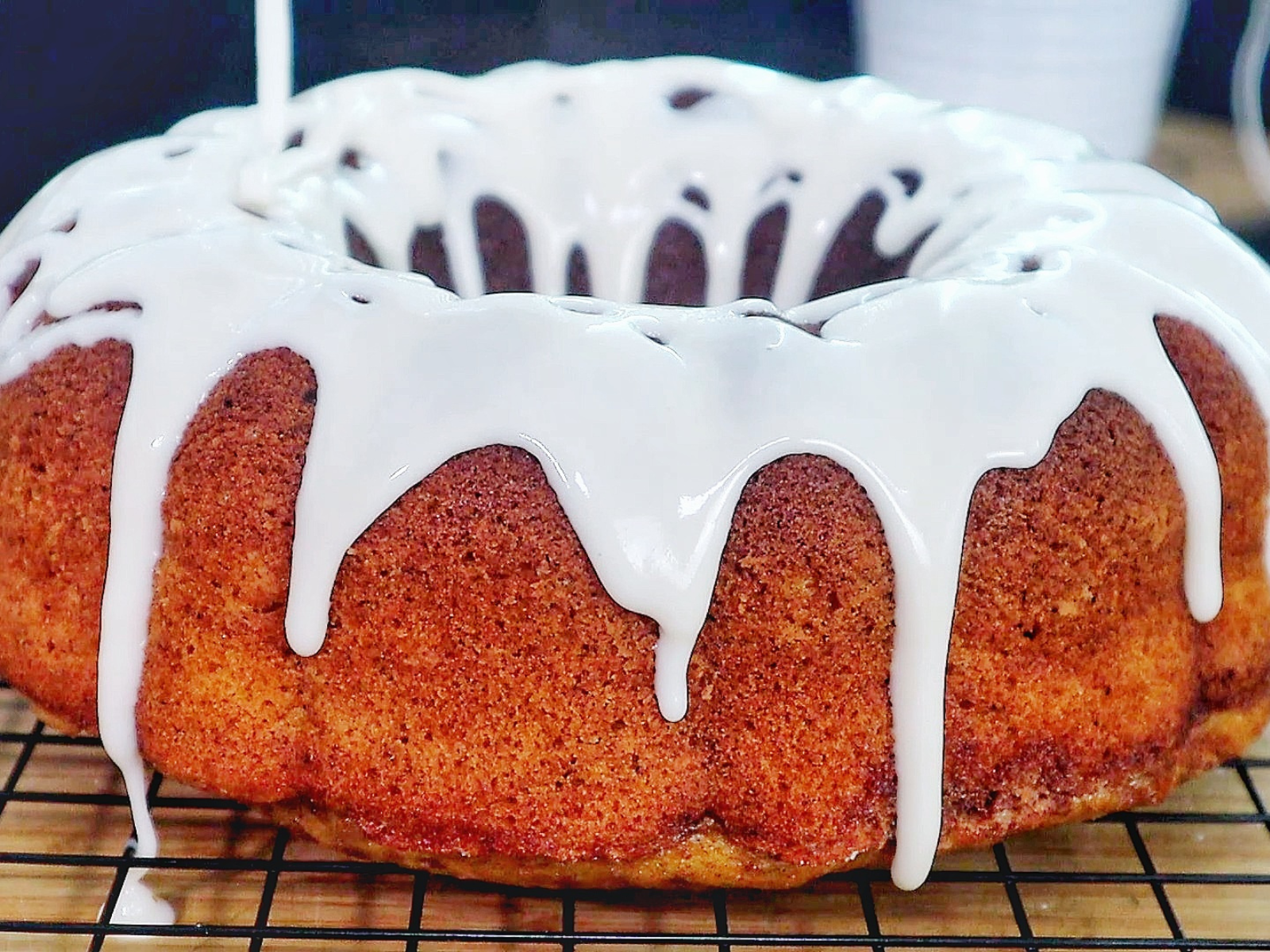 A moist sweet potato bundt cake topped with a smooth vanilla glaze, dripping down the sides. 