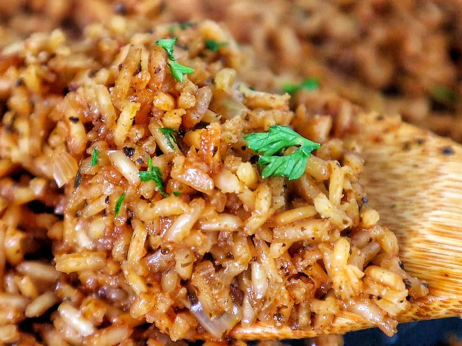 A close-up image of a skillet filled with golden-brown, seasoned rice garnished with fresh parsley, resembling the original recipe for Texas Roadhouse seasoned rice side dish.