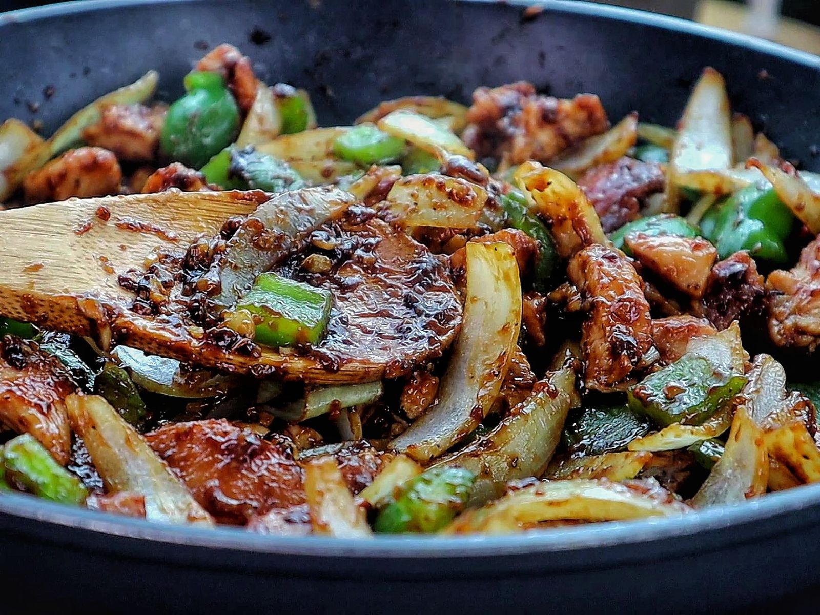 Sizzling black pepper chicken stir-fry with green bell peppers and onions coated in a rich black pepper sauce served in a skillet.