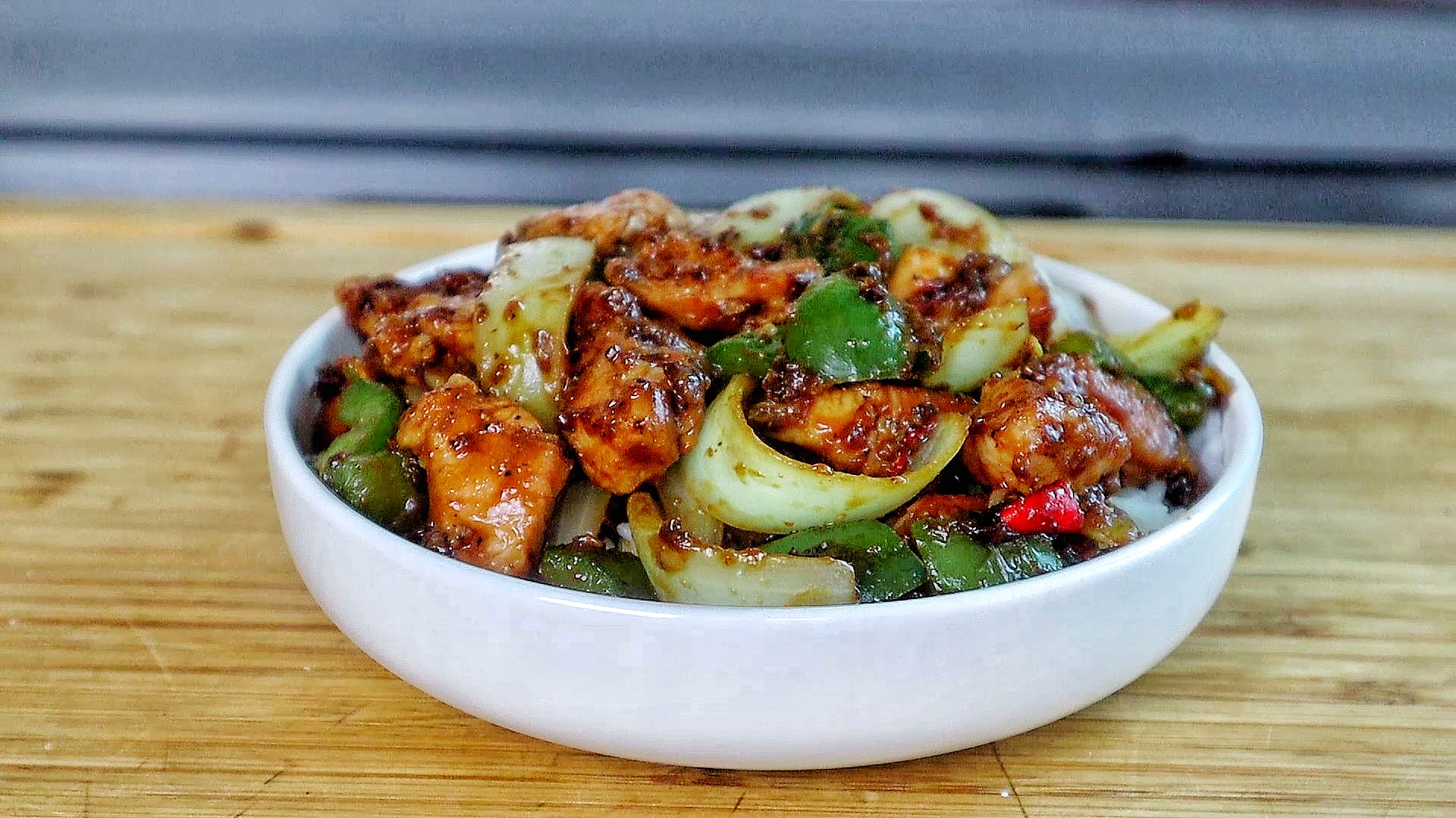 Sizzling black pepper chicken stir-fry with green bell peppers and onions coated in a rich black pepper sauce served in a skillet.