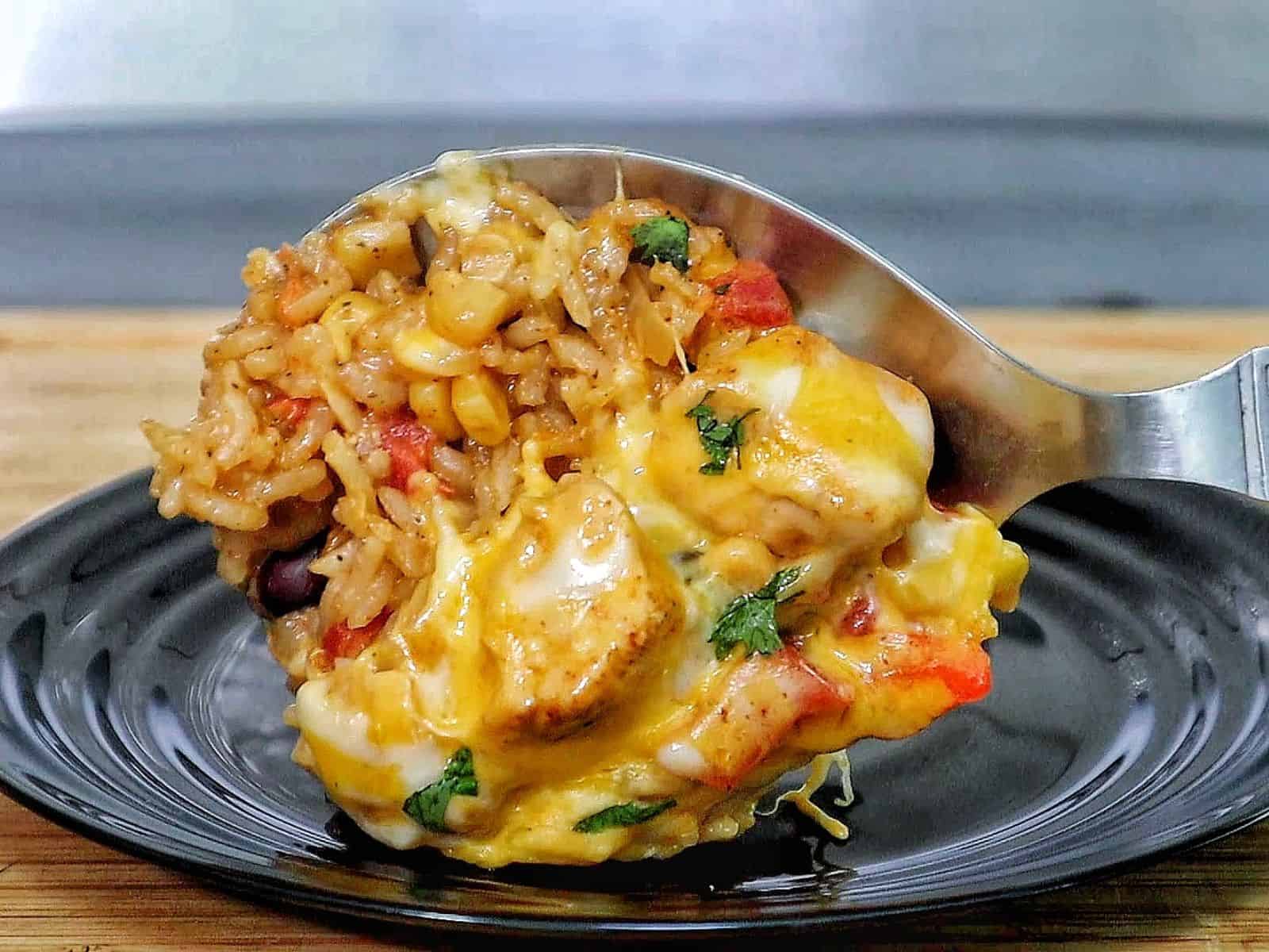 Cheesy chicken fajita rice casserole, showing bell peppers, melted cheese, and tender chicken scooped from a skillet.