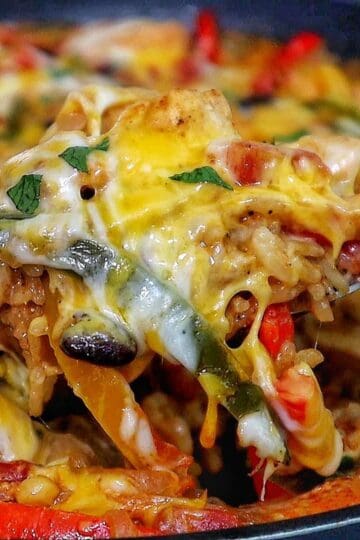 Cheesy chicken fajita rice casserole, showing bell peppers, melted cheese, and tender chicken scooped from a skillet.