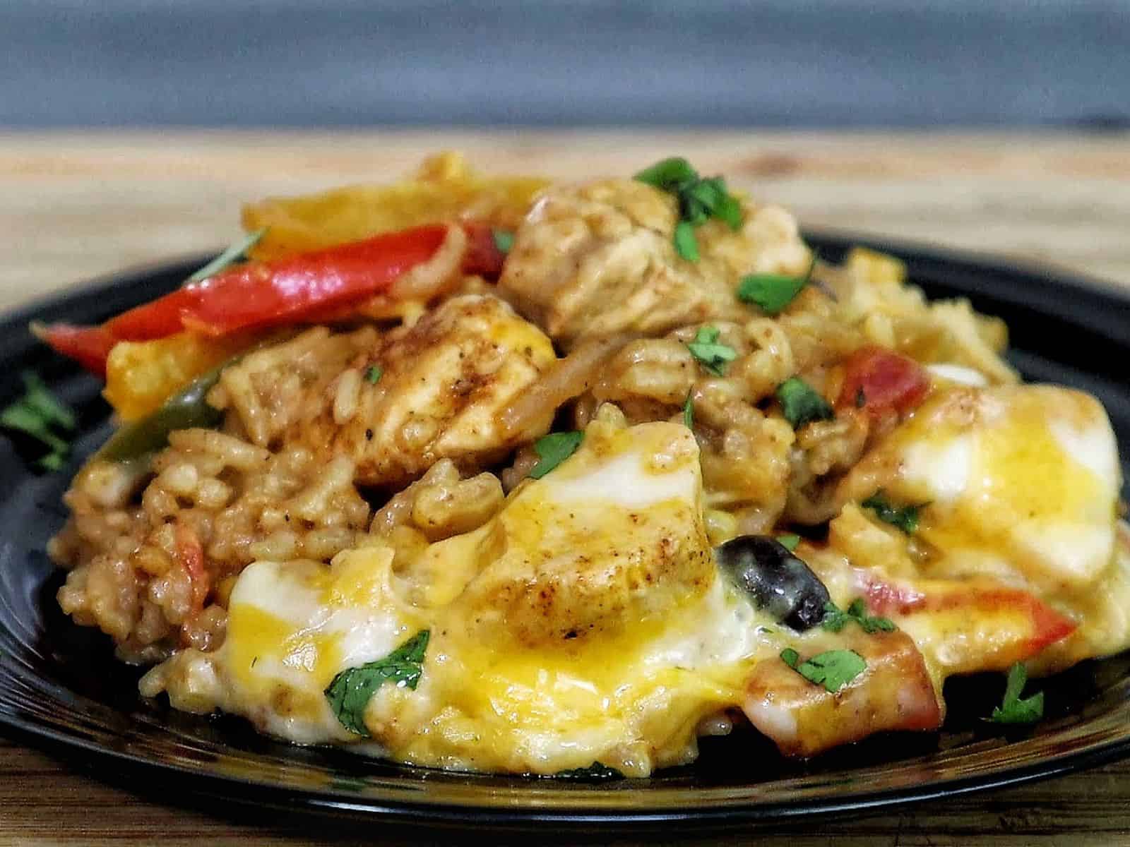 Cheesy chicken fajita rice casserole, showing bell peppers, melted cheese, and tender chicken scooped from a skillet.