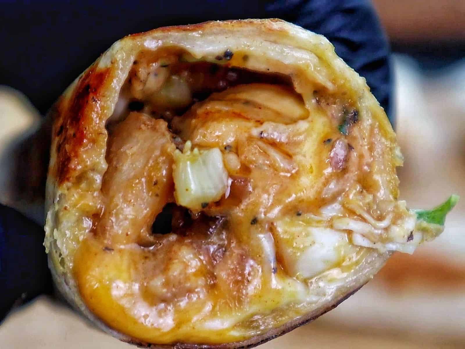 Golden-brown cheesy garlic chicken wraps, stuffed with melted cheese and tender chicken served on a black plate.