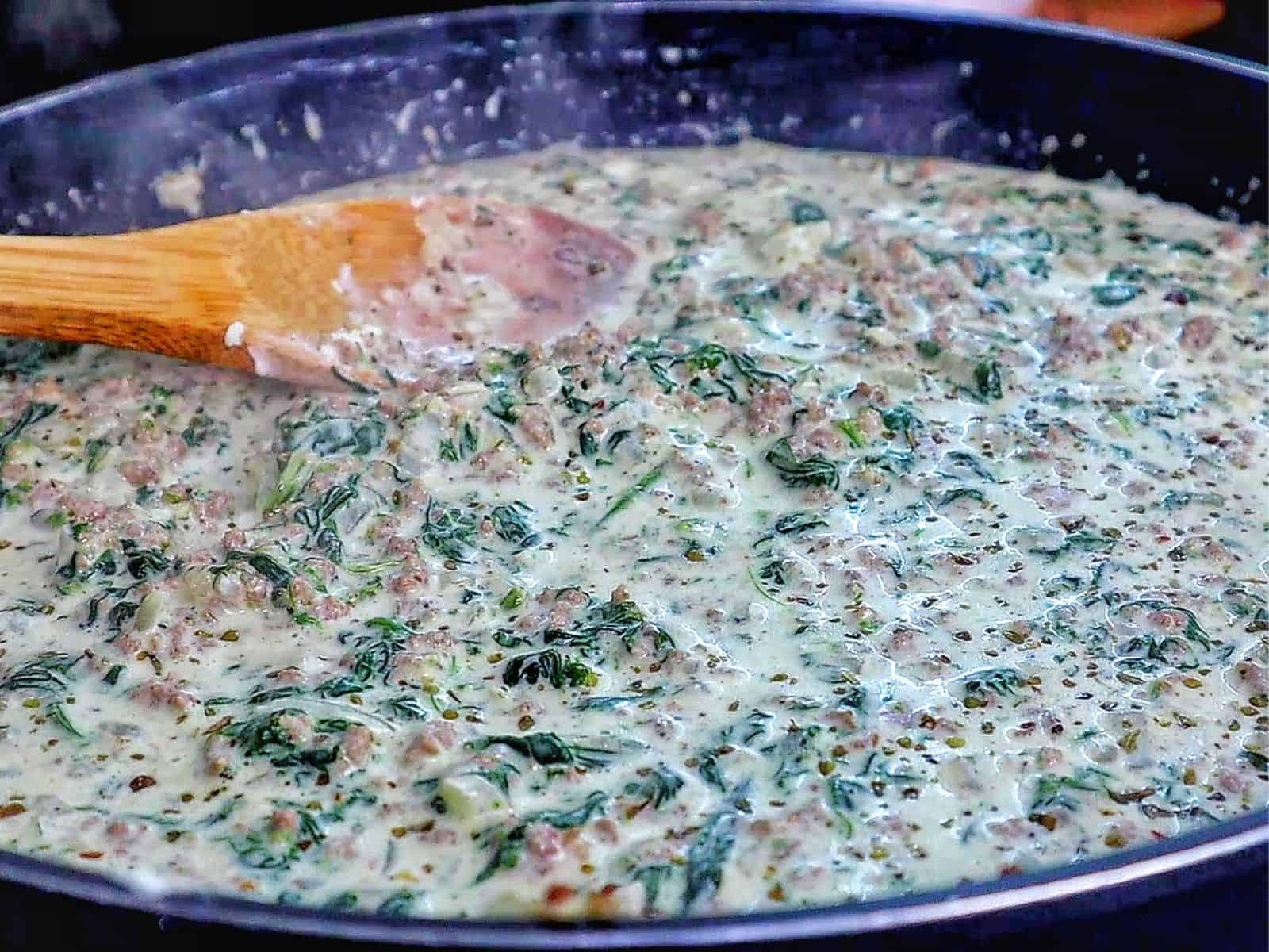 creamy ground beef and spinach casserole in a baking dish, with gooey melted cheese stretching and a golden, crispy topping.