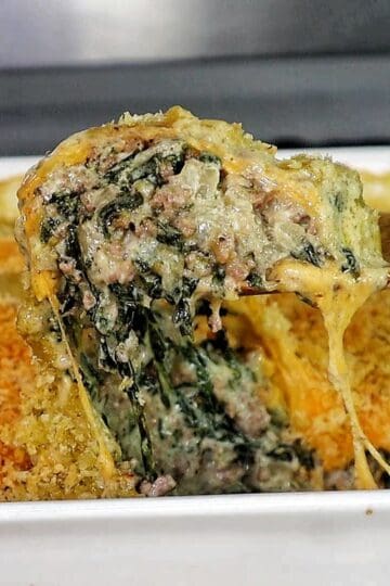 creamy ground beef and spinach casserole in a baking dish, with gooey melted cheese stretching and a golden, crispy topping.