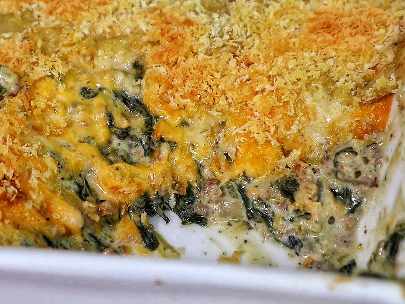 creamy ground beef and spinach casserole in a baking dish, with gooey melted cheese stretching and a golden, crispy topping.