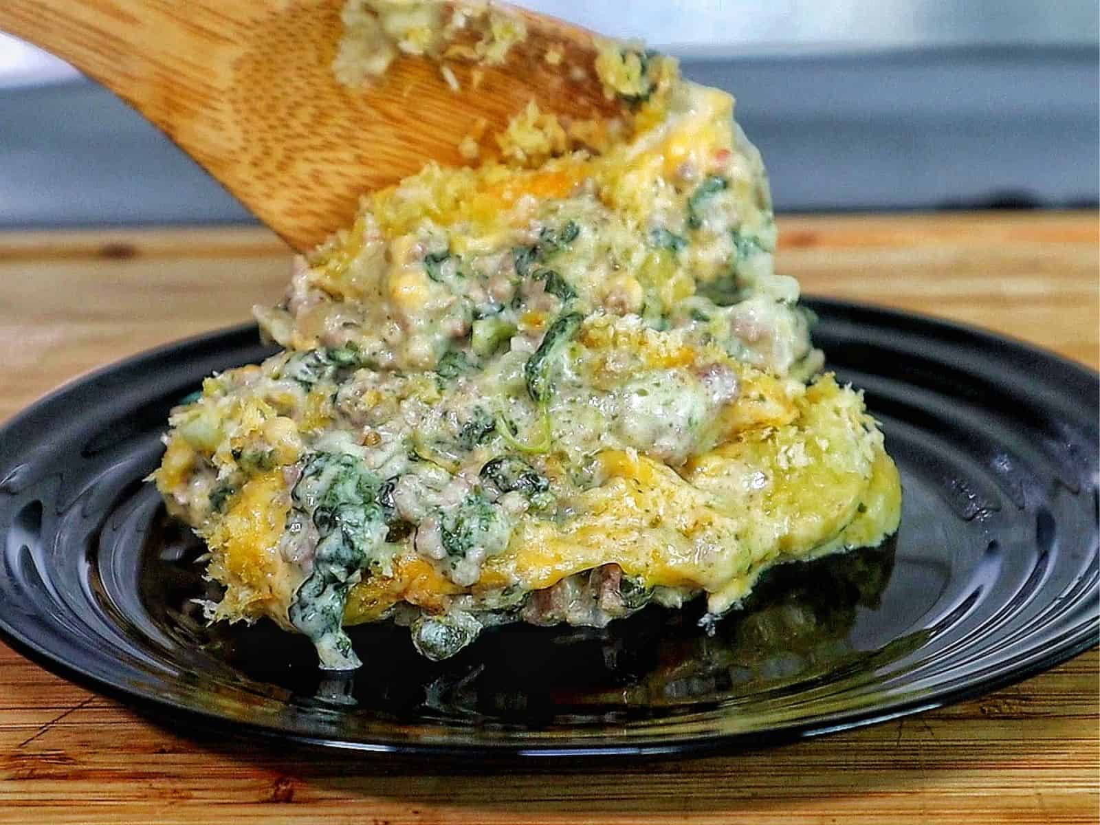 creamy ground beef and spinach casserole in a baking dish, with gooey melted cheese stretching and a golden, crispy topping.