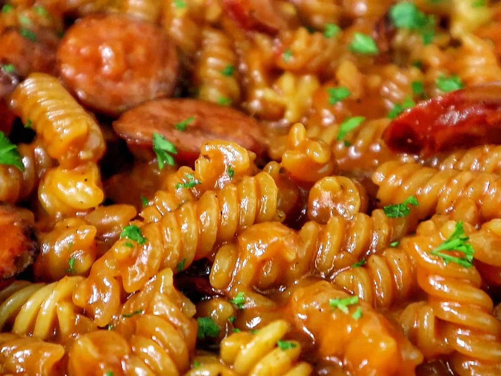 rotini pasta coated in a rich honey BBQ sauce with sliced sausage and garnished with fresh parsley