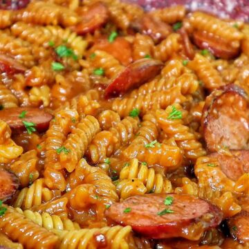 rotini pasta coated in a rich honey BBQ sauce with sliced sausage and garnished with fresh parsley