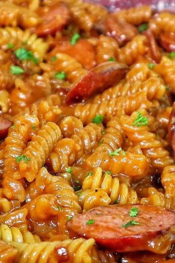 rotini pasta coated in a rich honey BBQ sauce with sliced sausage and garnished with fresh parsley