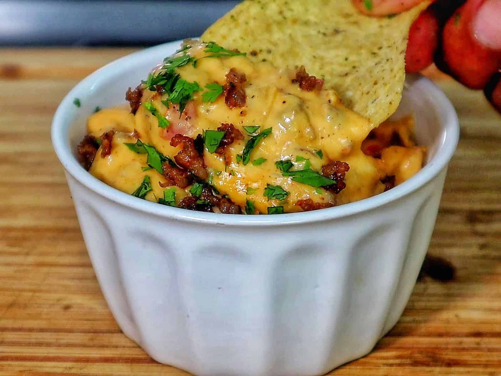 Creamy Ranch Rotel queso dip topped with browned sausage crumbles and garnished with fresh chopped parsley.