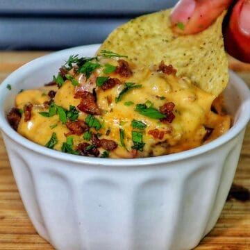 Cheesy Ranch Rotel queso dip topped with browned sausage crumbles and garnished with fresh chopped parsley.