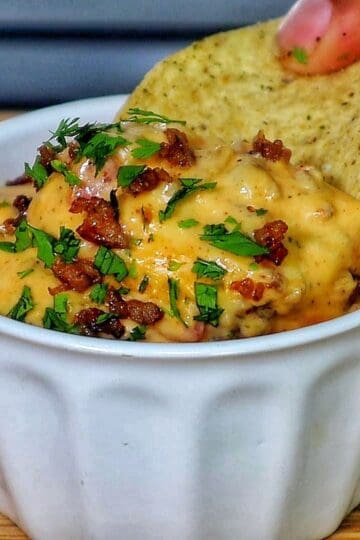 Cheesy Ranch Rotel queso dip topped with browned sausage crumbles and garnished with fresh chopped parsley.