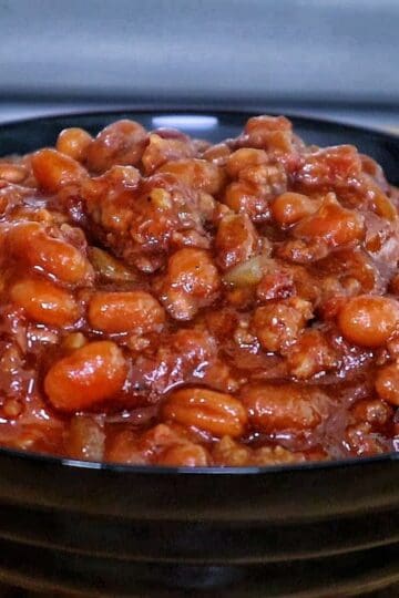 A cast-iron skillet filled with sweet and smoky baked beans simmering on a grill.
