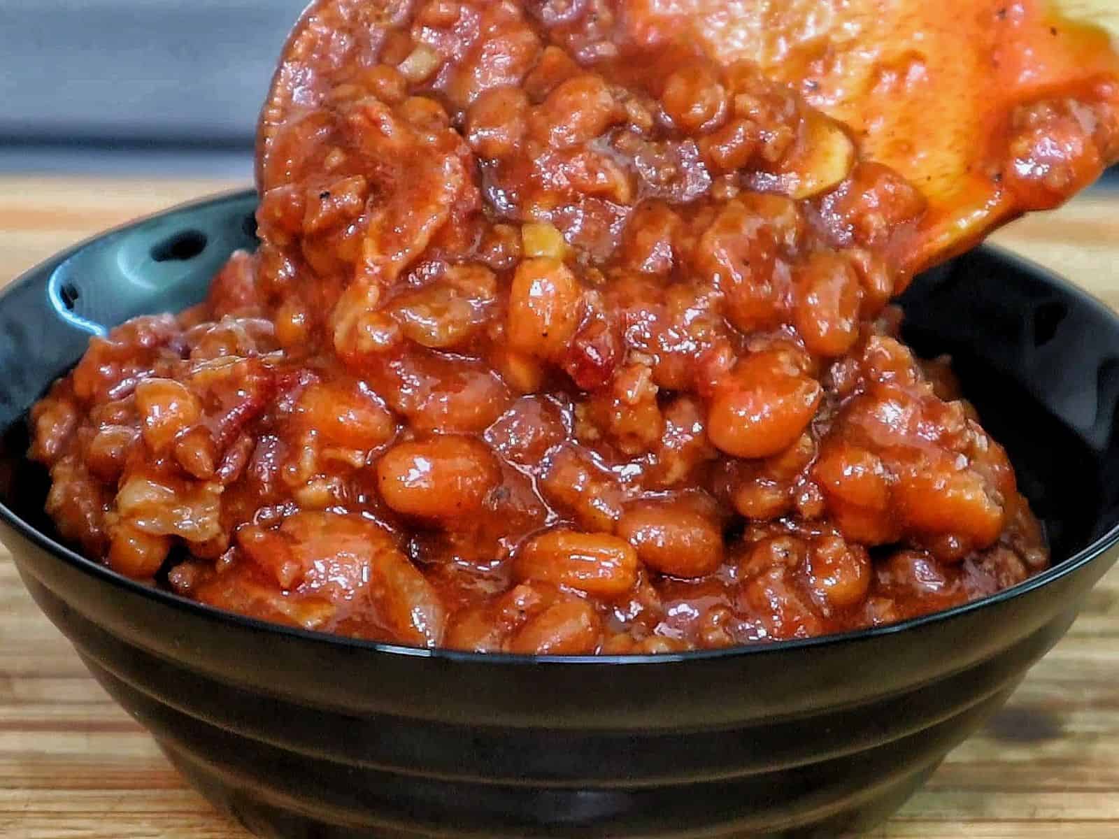 A cast-iron skillet filled with sweet and smoky baked beans simmering on a grill.