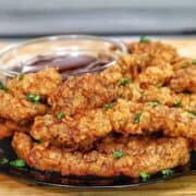 golden-brown crispy steak fingers, garnished with fresh parsley, served with a side of dipping sauce.