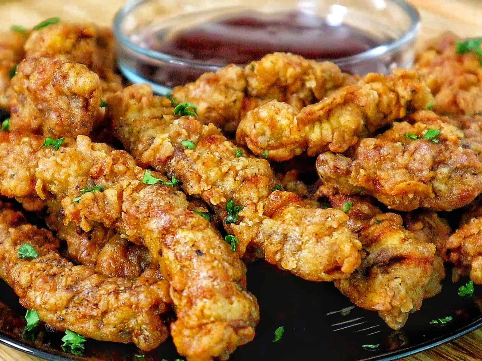 golden-brown crispy steak fingers, garnished with fresh parsley, served with a side of dipping sauce.