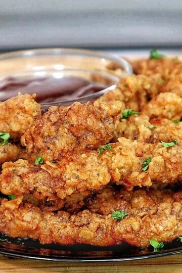 golden-brown crispy steak fingers, garnished with fresh parsley, served with a side of dipping sauce.