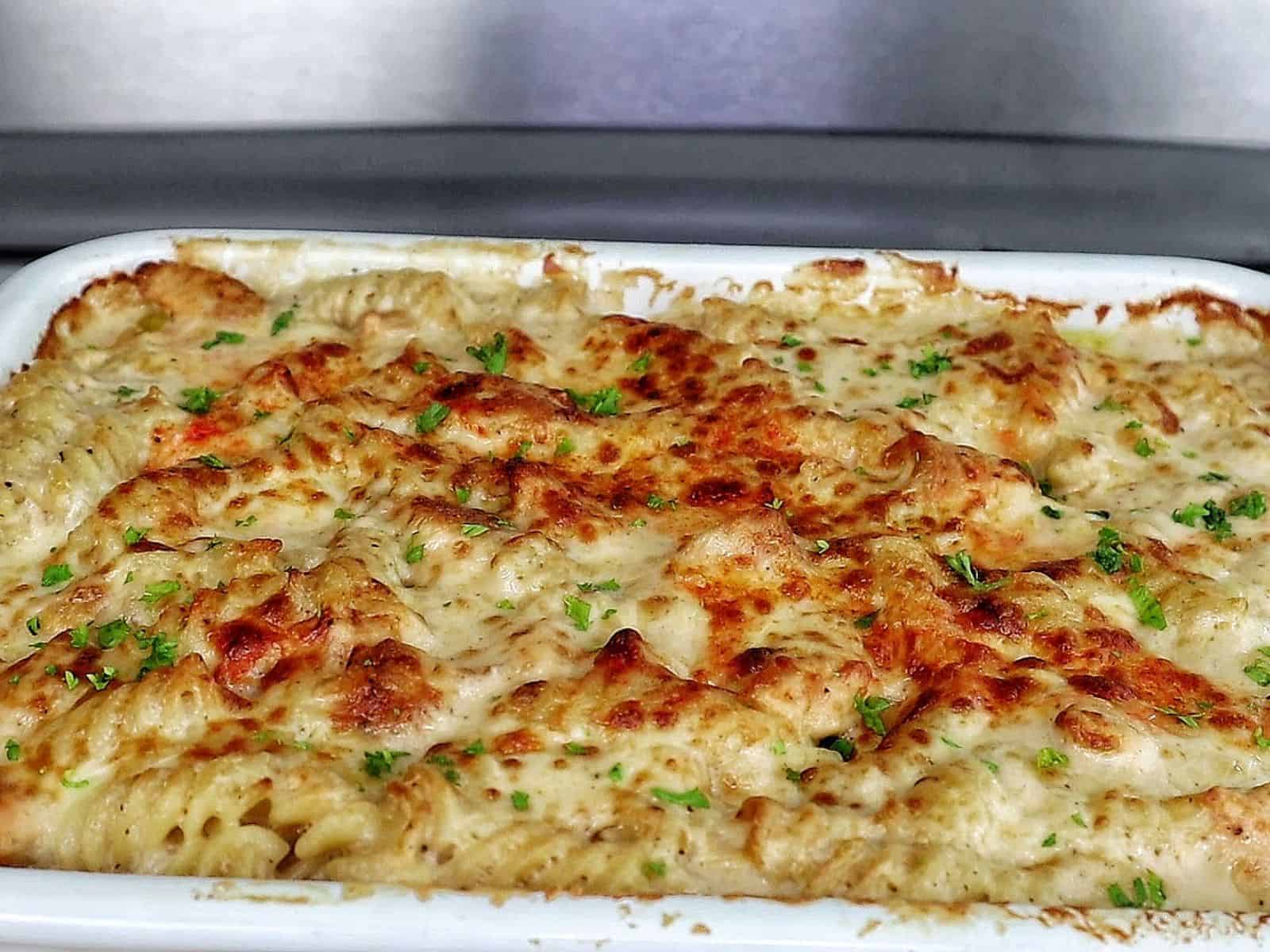golden-brown baked garlic parmesan chicken pasta, topped with bubbly melted cheese and garnished with fresh parsley