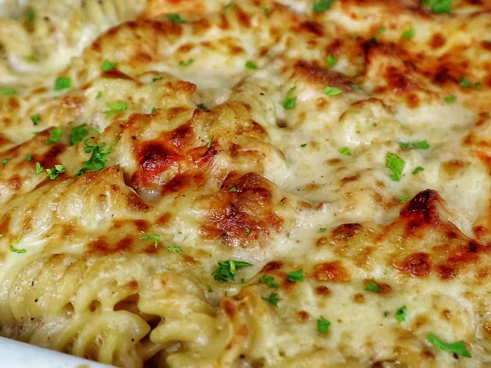 golden-brown baked garlic parmesan chicken pasta, topped with bubbly melted cheese and garnished with fresh parsley