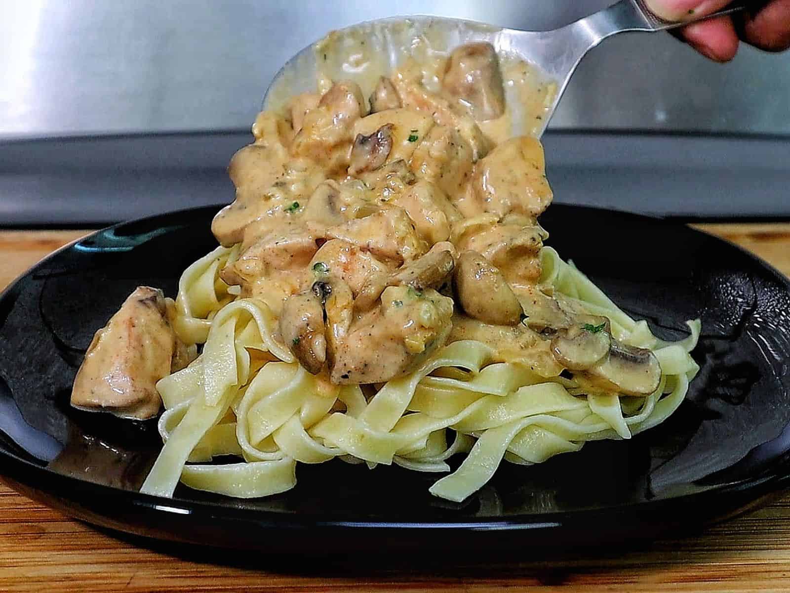 creamy chicken mushroom stroganoff, featuring tender chicken pieces and sautéed mushrooms coated in a rich, golden sauce, garnished with fresh parsley.