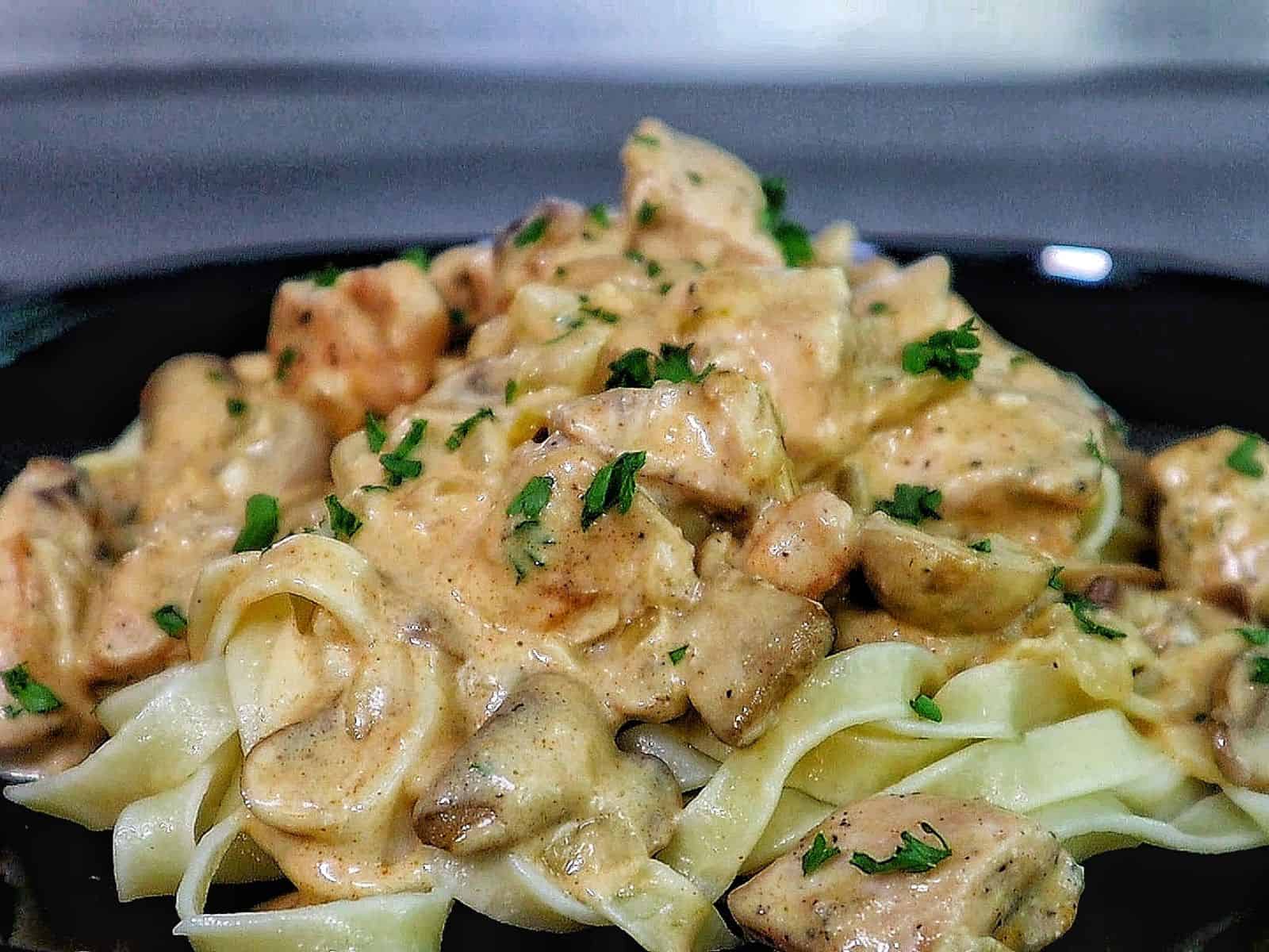 creamy chicken mushroom stroganoff, featuring tender chicken pieces and sautéed mushrooms coated in a rich, golden sauce, garnished with fresh parsley.
