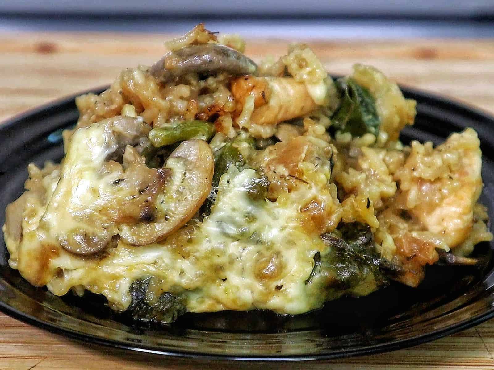 French Onion Chicken and Rice casserole with melted cheese, mushrooms, spinach, and tender chicken pieces baked together in a creamy rice mixture.