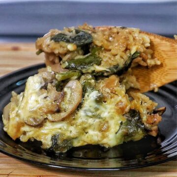 French Onion Chicken and Rice casserole with melted cheese, mushrooms, spinach, and tender chicken pieces baked together in a creamy rice mixture.