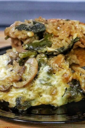 French Onion Chicken and Rice casserole with melted cheese, mushrooms, spinach, and tender chicken pieces baked together in a creamy rice mixture.